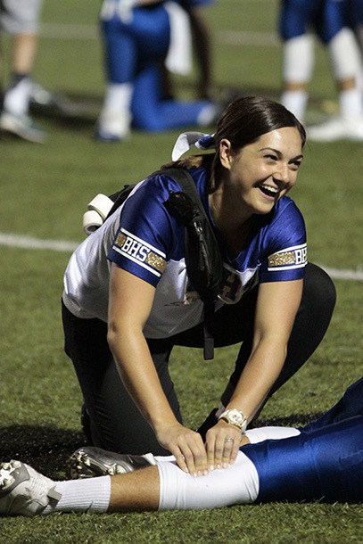 Bainbridge High School athletic trainer Amanda Sageser attends to a downed athlete during a recent home football game.