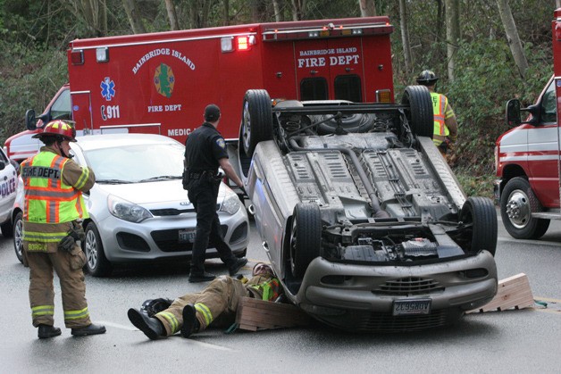 A Bainbridge Island firefighter tries to get a good look inside an overturned vehicle after a two-car crash on Highway 305 in Winslow Tuesday.