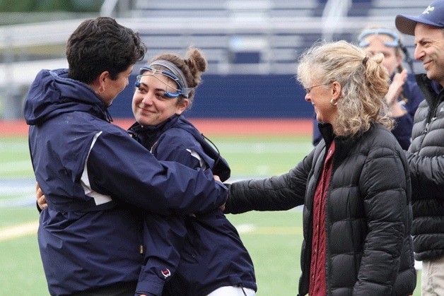 Spartan Coach Tami Tommila shares a hug with senior lacrosse player Sallie Marx while her parents watch during the Senior Night ceremony at Bainbridge's game against Lakeside.