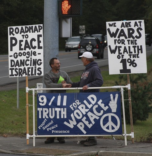 Peace activist Robin Hordon greets people on the street at the corner of High School Road and State Route 305.