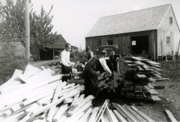 Four men move wood at the Koura farm during construction of the farmhouse in 1938. From left to right is Harold Raber