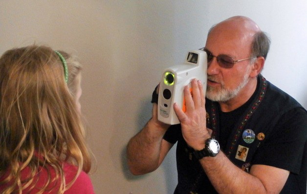 Poulsbo Lion Dave Risley uses the SureSight device to examine a child’s eyes at a recent eye clinic.