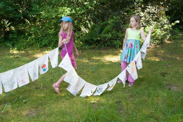 Montessori Country School third-graders Isabell Gacioch and Cadence Godfrey unveil “peace flags” during a special ceremony last week. The students took part in a rededication of a “Peace Pole” where students resolve conflicts.