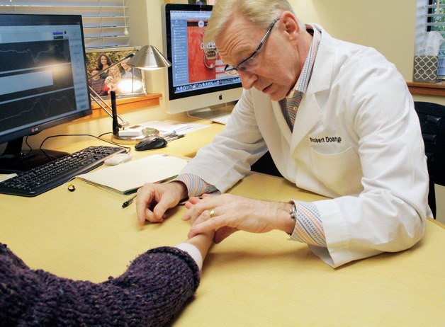 Robert Doane examines a patient’s wrist in preparation for an acupuncture treatment.