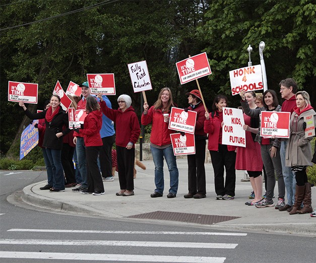 Teachers and supporters gather at the intersection of Highway 305 and Winslow Way Thursday with signs and slogans during the early morning commuter-heavy sailings to Seattle.