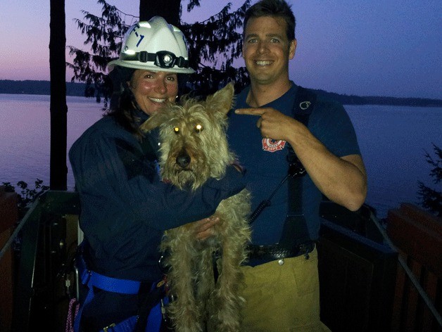 Firefighters Carol Mezen and Mike Finley stand with Shaman shortly after rescuing him from the side of a north island bluff.