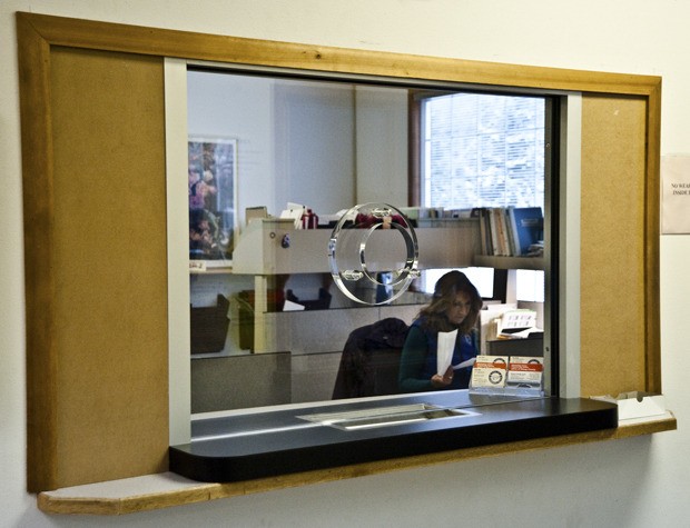 A courthouse staff member works behind a window of custom-made bullet proof glass.
