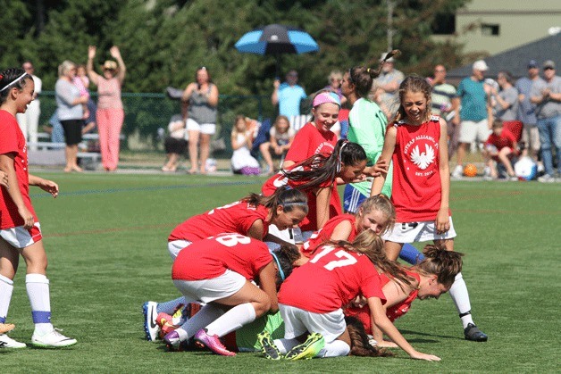 Members of the U10 Kitsap Alliance team mob their goalkeeper after winning in a dramatic shootout that won the team the title during Sunday’s final of the Island Cup Sunday.