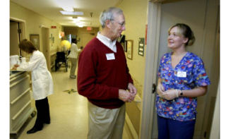 Recently re-elected State Sen. Phil Rockefeller talks with Monica Marschall CNA at Island Health and Rehabilitation Center on Wednesday. He spent three hours observing workers and assisting patients at the facility. As a member of the Ways and Means Committee in Olympia