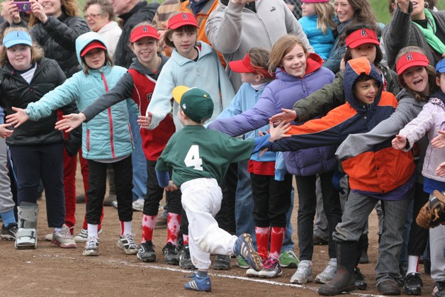 Bainbridge Island Little Leaguers crowd along the baseline to give Tee Ball players a high five as they run the bases at the close of this year's Opening Day Jamboree.