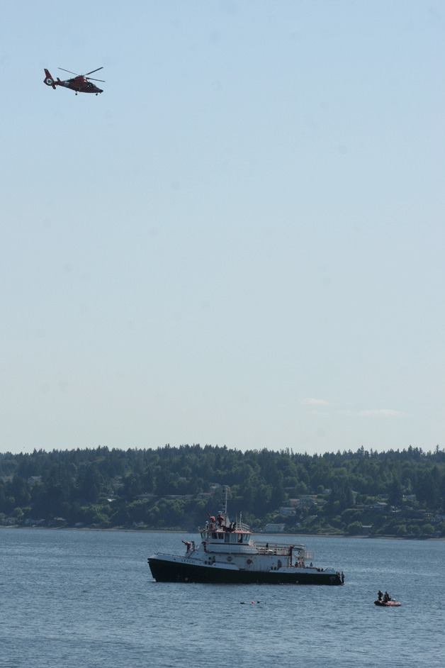 A Coast Guard helicopter hovers over the Seattle Fire Department fire boat Leschi as divers search the waters off South Beach for a missing diver Tuesday.
