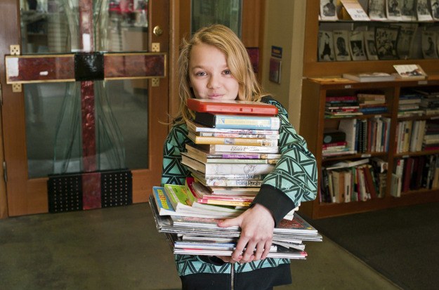 Voracious reader Elsa Knowlton emerges from the Bainbridge Public Library with a stack of books and other media. The library kicks off a year-long celebration of its 50th anniversary with a community event March 17.