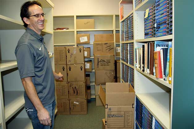 Woodward Middle School librarian Ian Patrick stands in his school’s library with boxes of old books that are no longer relevant to the student population. Patrick has “weeded” the library and hopes an online fundraiser can provide students with updated materials.