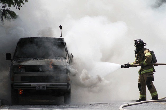 A firefighter is surrounded by a cloud of smoke as Bainbridge firefighters put out a vehicle fire on Wyatt Way Tuesday.