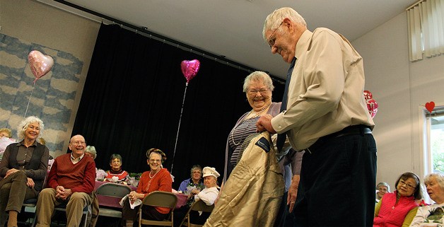 Barbara Hansen laughs as her husband Reid Hansen works his way out of his coat during the senior center fashion show.