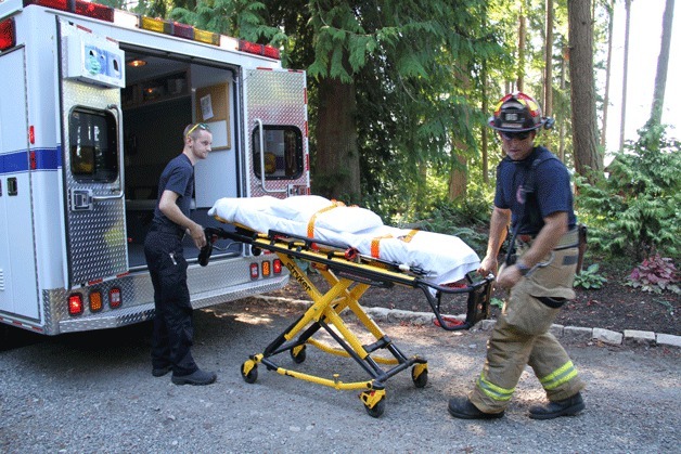 Emergency responders get ready to take a woman and her 3-year-old daughter to Harborview Medical Center Sunday after the girl went over the side of a cliff near Hidden Cove Road.