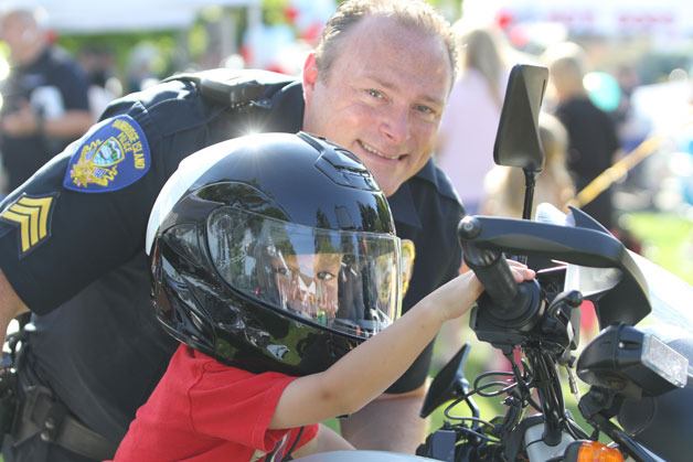 Bainbridge Police Officer Trevor Ziemba helps a youngster test out a BIPD motorcycle during last year’s National Night Out. Officers from the Bainbridge Island Police Department welcome the community to the 33rd annual National Night Out