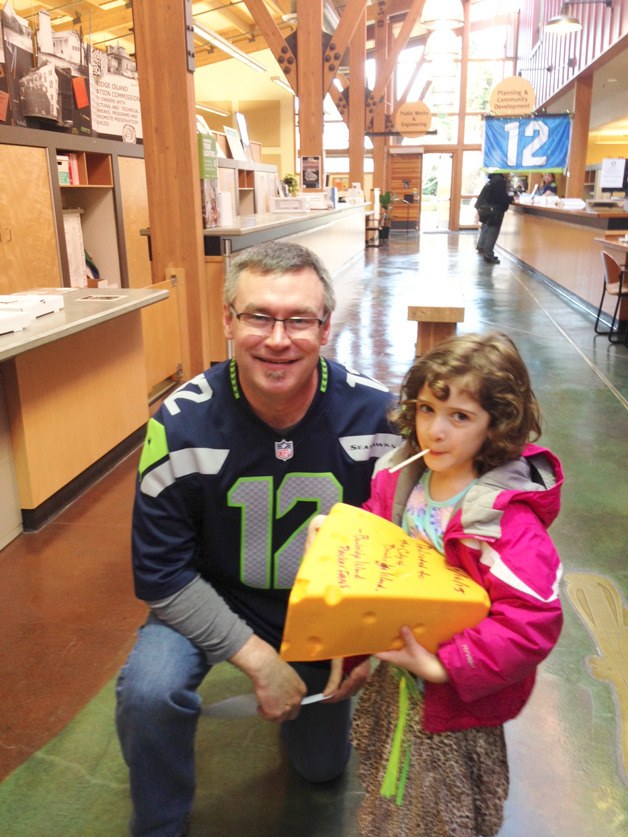 Bainbridge Island City Manager Doug Schulze receives a Green Bay Packers Cheesehead from 4-year-old Freya Streckenbach of Bainbridge Island. Freya is one of four children of Susan and Keith Streckenbach