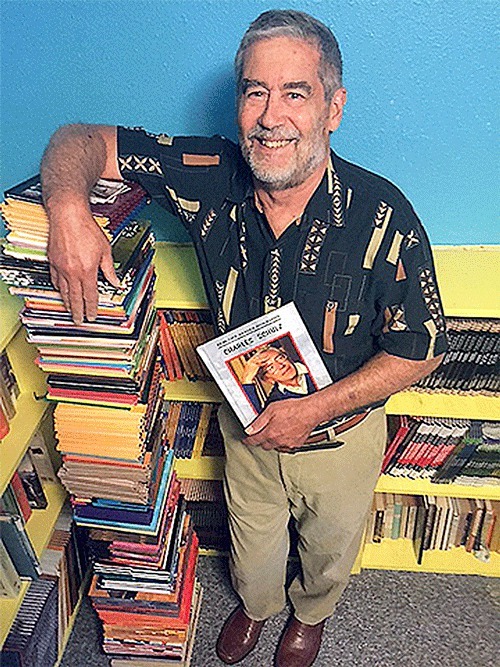 Jim Whiting stands next to a stack of books he’s authored.