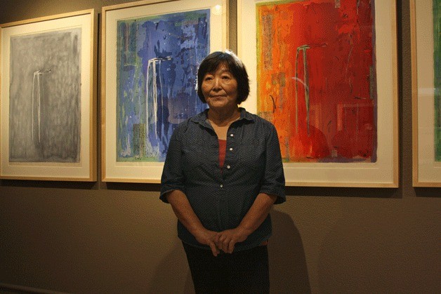 Keiko Hara stands in front of three pieces from her series