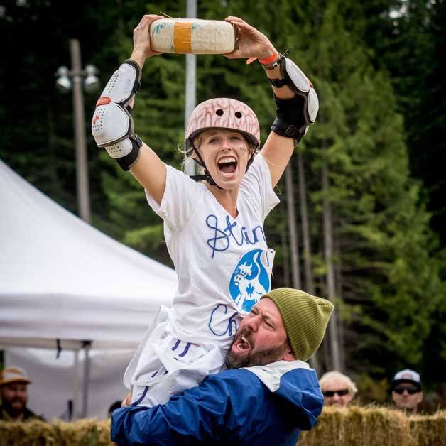 Rebecca Sharar hoists an 11-pound cheese wheel over her head after being declared the winner in the Canadian Rolling Cheese Festival women’s  championship race.