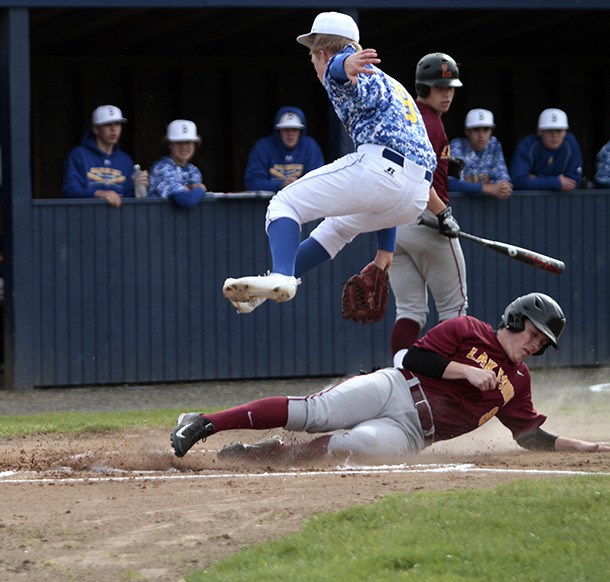 Bainbridge pitcher Jason Snare leaps to avoid a collision with a Lakeside runner sliding to home
