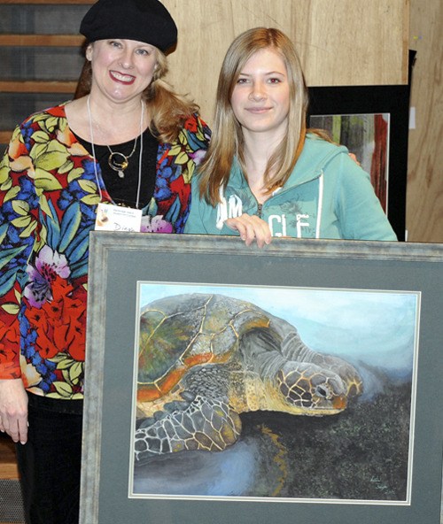 Bainbridge Student Art Contest founder and manager Dinah Satterwhite congratulates Island Odyssey eighth-grader Kristan Franzen who took Best of Show for “Turtle on Black Sand.”
