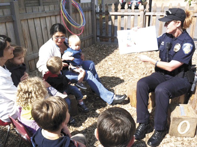 Photo courtesy of Carla Sias Bainbridge Island Police Officer Carla Sias reads from the picture book “Officer Buckle and Gloria” to the children at the Peacock Family Center.