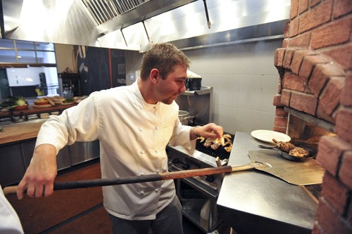 The Local Harvest restaurant opened last week at the Pavilion. Chef and owner Dan Miller checks the status of an order cooking in his brick fired oven. The restaurant features Northwest dishes served in the tapas style.