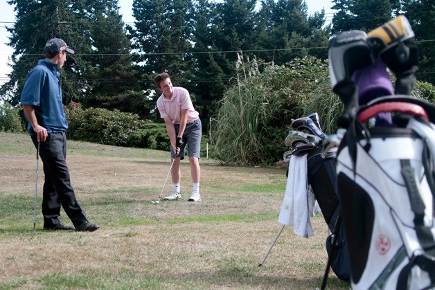 Spartan Head Coach Joe Lanza watches as one of his Bainbridge players tees off at Wing Point Golf Course.