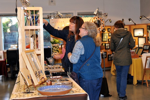 An artist on a recent tour shows her handiwork to a Bainbridge visitor. Artists can now submit applications to participate in the 2016 Bainbridge Island Summer and Winter Studio Tours.