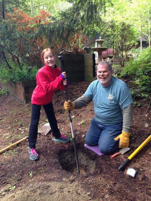Cora Drury helps Scott Sherman dig a hole to stake the Little Free Library outside 6575 Honeysuckle Lane. “It took him about a month [to build]
