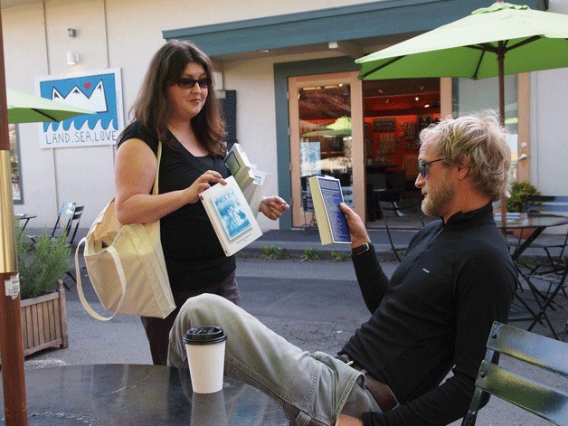 Katie Butler meets a lounging coffee drinker on Madrone Lane and presents him with a copy of “Peace Like a River” and “The Glass Castle” for World Book Night.