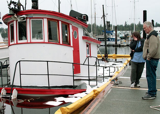 Bystanders look at the tugboat Chickamauga while it slowly sinks in Eagle Harbor in October 2013.