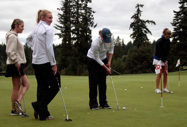 Members of the Bainbridge High School varsity girls golf team practice on the putting green at Wing Point Golf  & Country Club.