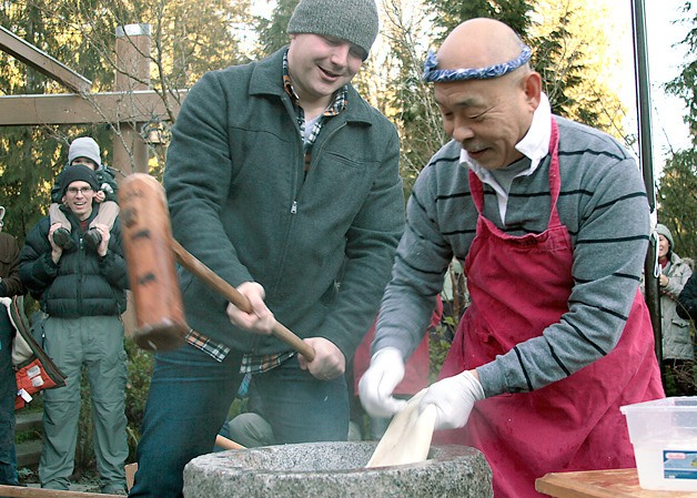 Andrew Wozniak takes a turn at pounding the steamed rice with a large wooden mallet