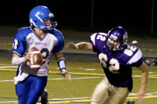 (Top) Junior quarterback Jason Haley looks for an open receiver with a North Kitsap defender in hot pursuit. Haley was just 3 of 10 for 81 yards and was on the run for much of the night as the Spartans lost to the Vikings 33-7 Saturday at North Kitsap.