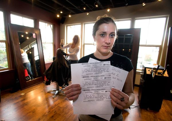 Carisa Crone holds copies of fake postal money orders that were sent to an employee at Studio M Salon & Spa. The fraudlent money orders were for a month of booked massages for an Italian model