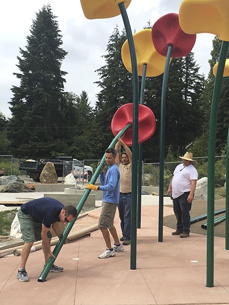 Parks staff and volunteers mount 'lollitops' in preparation for Owen's Playground's grand opening on Saturday.
