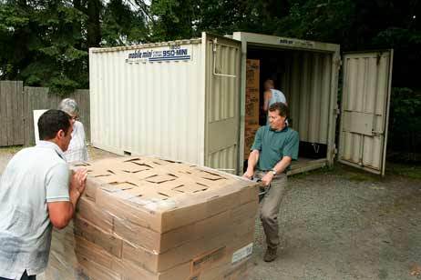 SeaShare's Jim Harmon (right) pulls a pallet of canned wild Alaska salmon toward a storage unit at Helpline House earlier this week