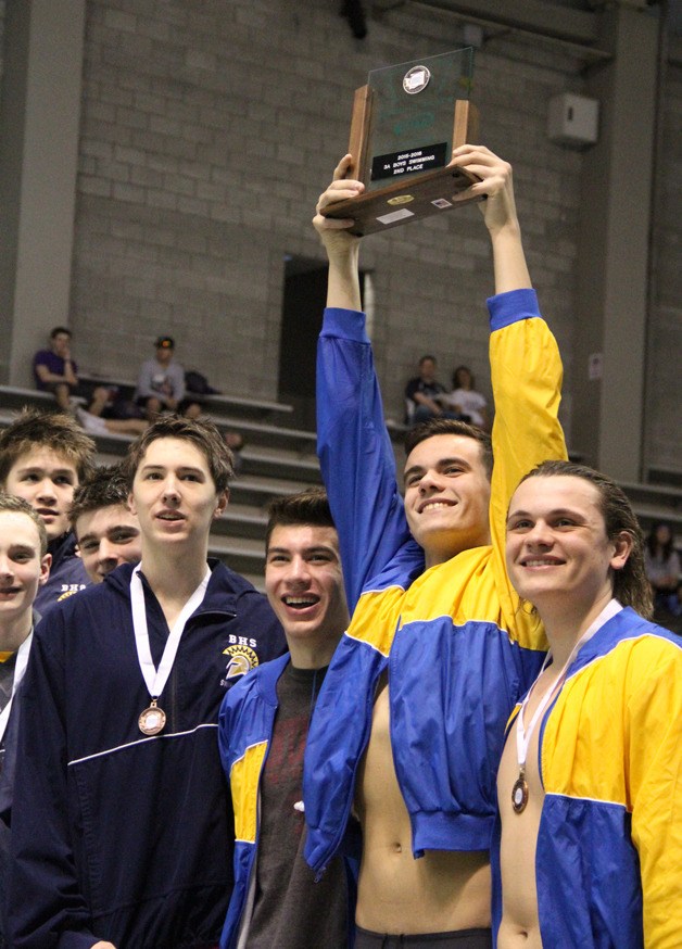 The Bainbridge Spartans boys swimming and diving team hoist the second-place team trophy from the medal stand at the close of the 3A state championships in Federal Way.
