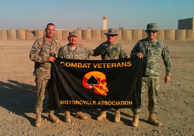 Military members in Afghanistan hold the Combat Veterans flag.