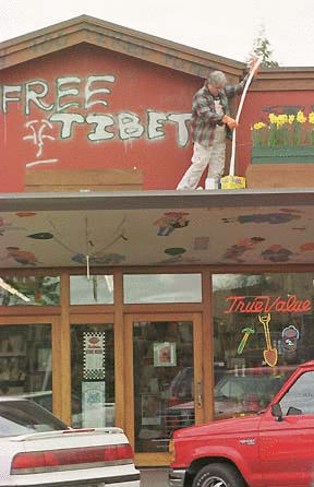 Volunteer Bruce Ziebart cleans graffiti from the Winslow Hardware facade.