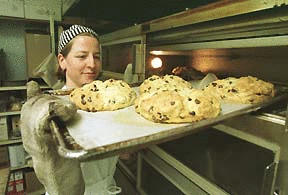 Heidi Umphenour pulls a fresh tray of Irish soda bread from the oven at Blackbird Bakery Tuesday morning. The bakery usually sells out of the bread by noon.