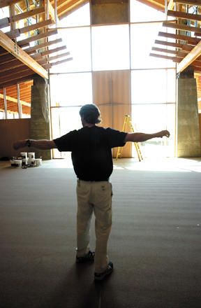 The Rev. Bill Harper takes in the sanctuary at the new Grace Episcopal Church building on Day Road East. Note the cross – serving dual purpose as functional structural steel – in the wall of windows.