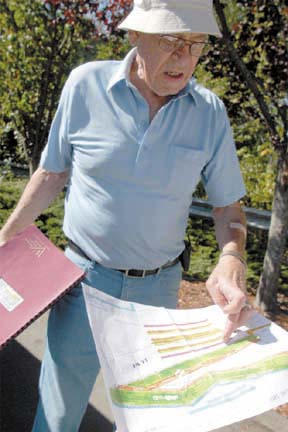 Larry Stutsman reviews plans next to the ravine north of Winslow Way and west of the highway