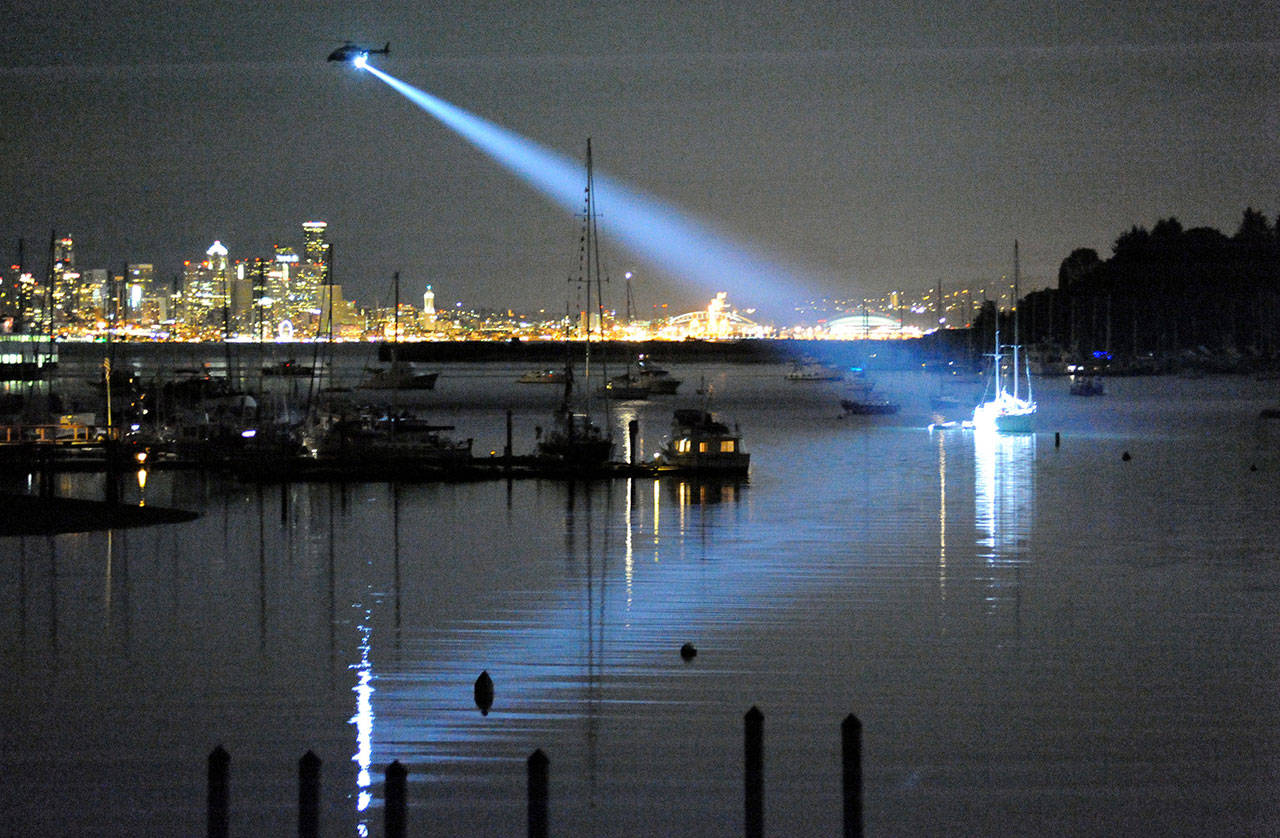 Dinah Satterwhite photo                                King County Sheriff’s Department’s Guardian One helicopter shines a spotlight on the sailboat owned by a Seattle man after he began firing from the boat at the shoreline of Eagle Harbor.