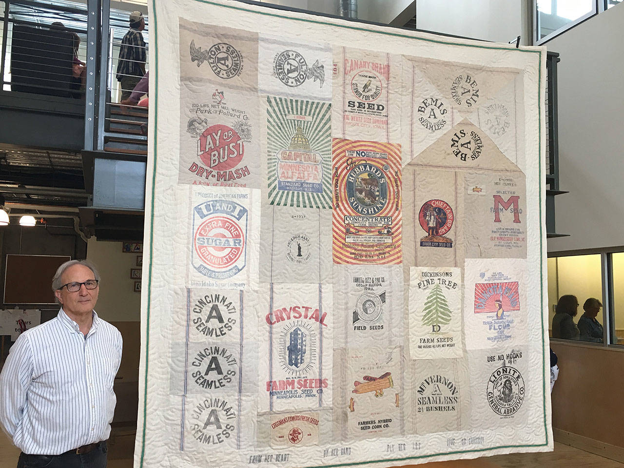 Photo courtesy of Kathy Dwyer. Phil Winer stands beside his quilt consisting of some 20 feed bags from the 1930’s.