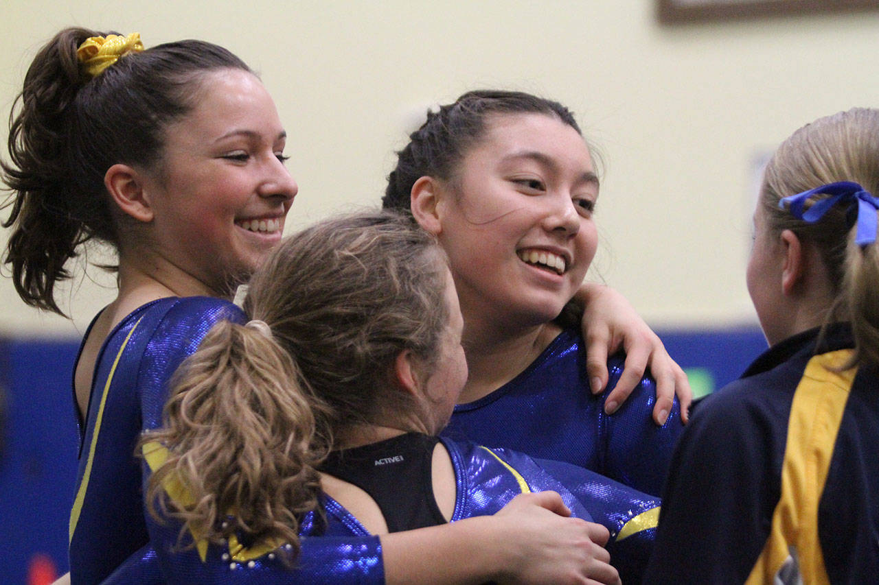 Mariko Ronan is congratulated by her Spartan teammates after her floor exercise routine during last week’s home meet. (Brian Kelly | Bainbridge Island Review)