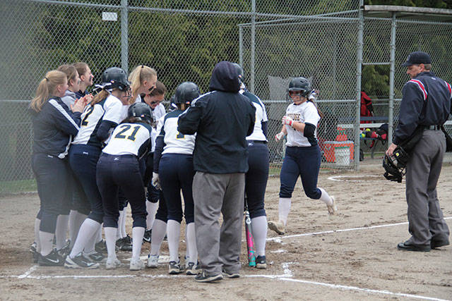 Maddie Loverich is greeted at home plate by her teammates after hitting a grand slam home run against Ingraham. (Brian Kelly | Bainbridge Island Review)